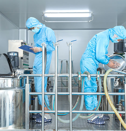 Workers wearing standard production hygiene clothing is operating emulsifying equipment