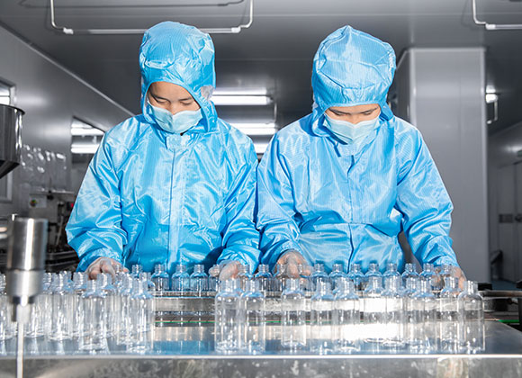 The workers are filling skin care products in the filling workshop wearing clean clothes